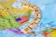 Ilustrační fotografie mapy USA, vlajky a vyskládaných písmen TARIFFS
