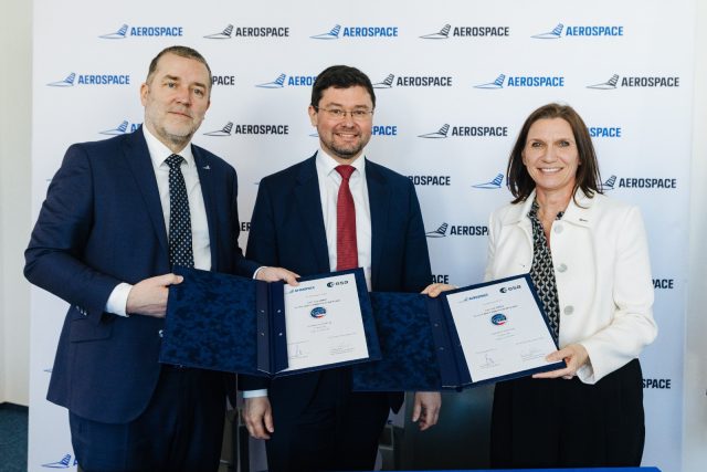 Žena a dva muži pózují s deskami, na kterých je smlouva o projektu AMBIC