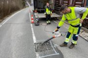 Muž v reflexním oblečení opravuje silnici novou technologií.