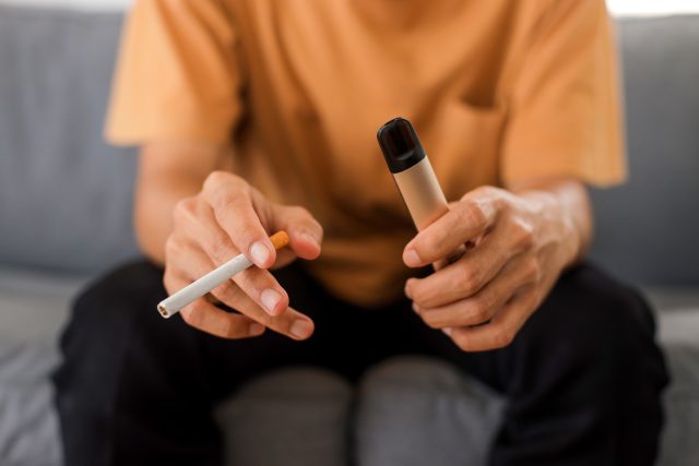 Ilustrační fotografie muže s klasickou a elektronickou cigaretou